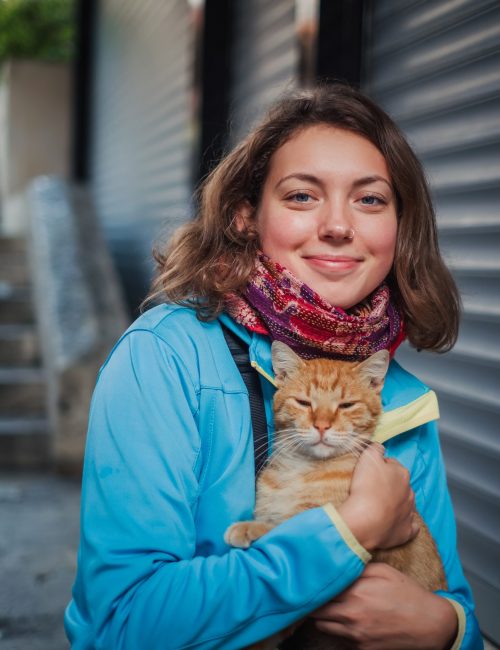 Portrait of beautiful woman that paying with red homeless cat. Love and fun emotion for pets